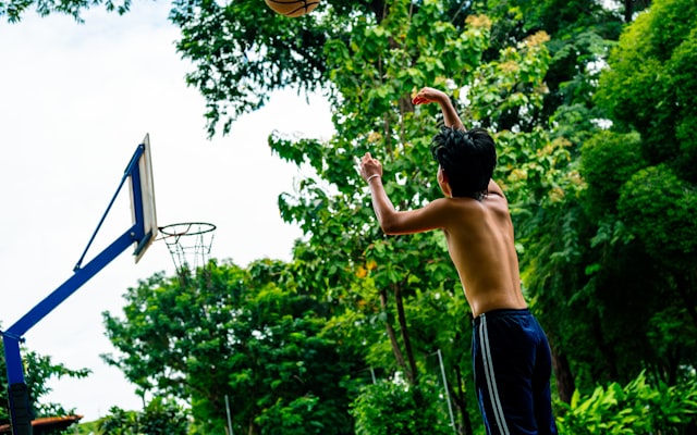 Teenager shooting basketball outdoors