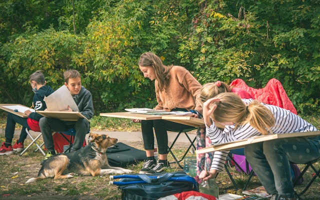Children drawing outdoors with dog