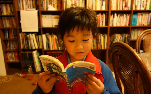 Child reading in front of bookshelves